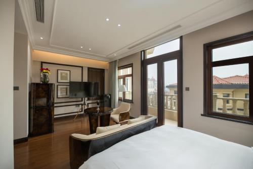 een slaapkamer met een bed, een bureau en een televisie bij 青岛阿特拉酒店 in Qingdao