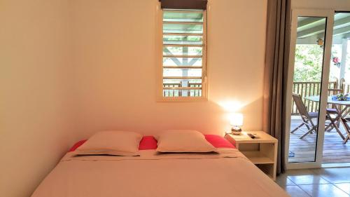 a bedroom with a bed and a balcony with a table at L´Odyssée Des Anses in Les Anses-dʼArlets