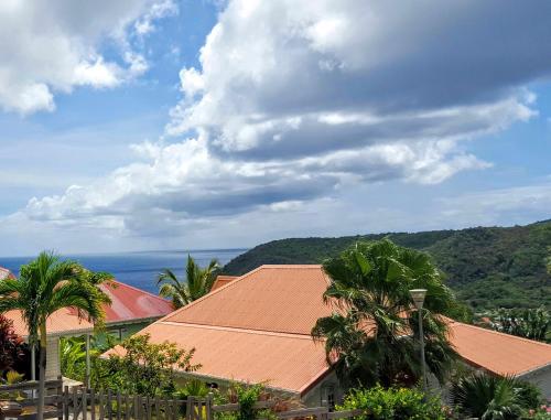 a view of a building with palm trees and the ocean at L´Odyssée Des Anses in Les Anses-dʼArlets