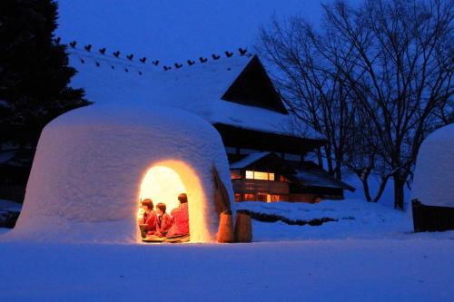 a group of people sitting in an igloo in the snow at Hostel&Bar CAMOSIBA in Yokote