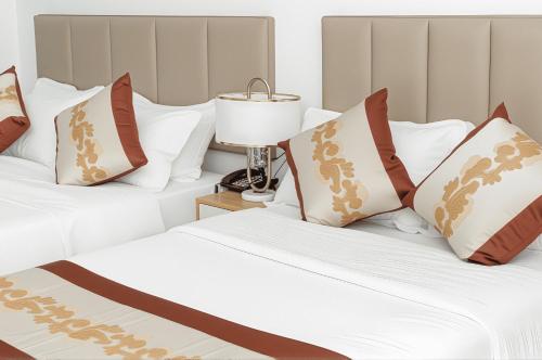two beds in a bedroom with white and brown pillows at Vienna Hotel VN in Ho Chi Minh City