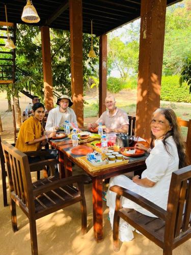 eine Gruppe von Menschen sitzt um einen Holztisch in der Unterkunft Habarana Tree House - Ivory cottage in Habarana