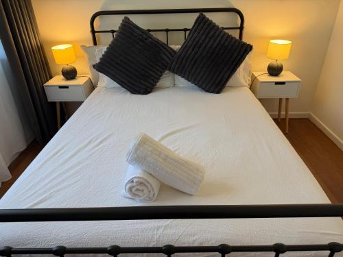 a bed with a towel on it with two lamps at 3BR Comfy Home, Gym & Garden in The Gap in The Gap