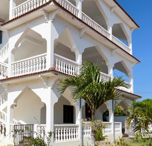 een wit gebouw met een palmboom ervoor bij Diamond Luxury Homes in Watamu