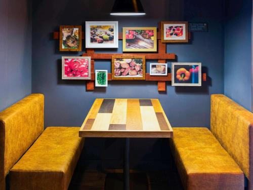 a table and benches in a room with pictures on the wall at ibis budget Birmingham Airport Terminal Building - NEC in Bickenhill