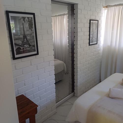 een slaapkamer met een witte bakstenen muur en een spiegel bij Linga longa corner flat in Beaufort West