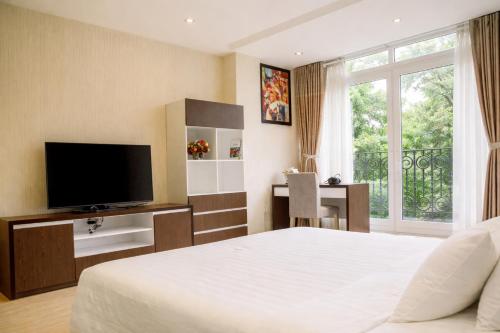 a bedroom with a bed and a television and a desk at Golden Queen Aparthotel in Ho Chi Minh City