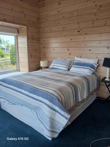 een slaapkamer met een bed met een houten muur bij A Waihi Beach Getaway in Waihi Beach