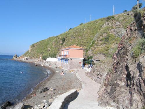 a building on the side of a hill next to the water at Panselinos Hotel in Mithymna