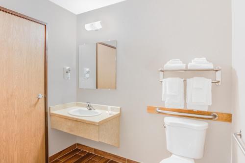 a bathroom with a toilet and a sink and a mirror at Super 8 by Wyndham Green Bay Near Stadium in Green Bay