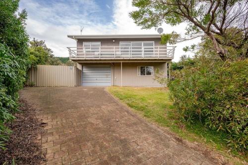 een huis met een veranda en een garage bij Sea View Batch in Takaka