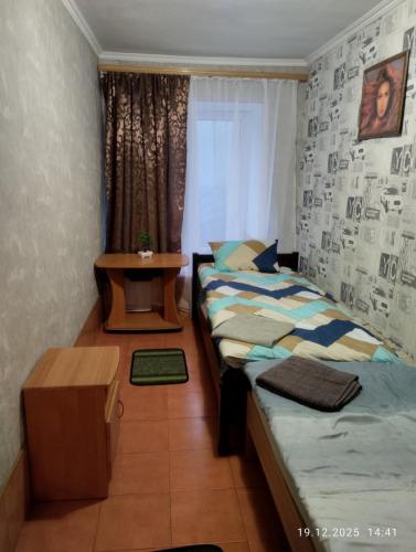 ein Schlafzimmer mit zwei Einzelbetten und einem Tisch in der Unterkunft Optimal 1 in Kiew