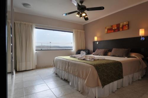 - une chambre avec un grand lit et un ventilateur de plafond dans l'établissement Madeo Hotel & Spa, à Villa Carlos Paz