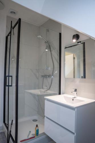 a white bathroom with a shower and a sink at Apartment - 3 guests in Mont-Saint-Guibert
