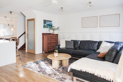 een woonkamer met een zwarte bank en een tafel bij Whitsunday Wanderluxe in Cannonvale