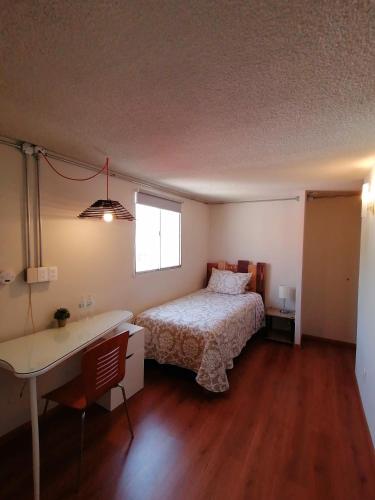 a bedroom with a bed and a desk and a window at Casagrande in San José de Malpaso