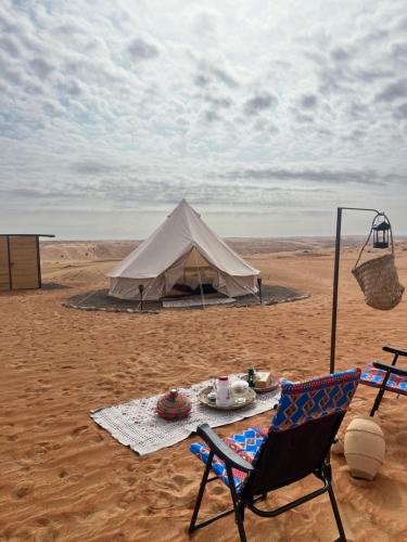namiot na pustyni ze stołem i krzesłem w obiekcie Quiet Nights Camp w mieście Badīyah