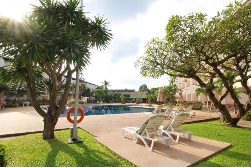 a row of lounge chairs next to a swimming pool at Hotel Tropicana Pattaya in Pattaya Central