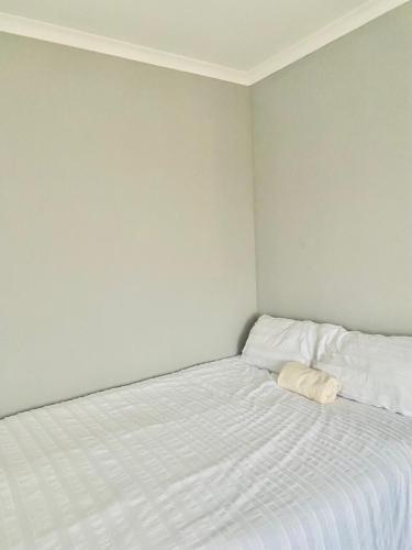 a bedroom with a white bed with a pillow on it at Pluto Guesthouse in Walvis Bay