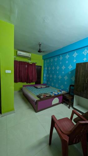 a bedroom with a bed and a chair in it at Ashirbad hotel in Digha