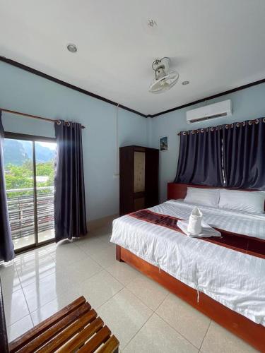 a bedroom with a bed and a chair and a window at VangVieng Smile guesthouse in Vang Vieng