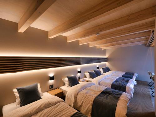 a bedroom with three beds and a ceiling with beams at KONA RESORT AWAJI KAI in Awaji