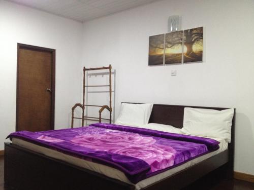 a bed in a room with a purple blanket at Nuwara Eliya Homestay in Nuwara Eliya
