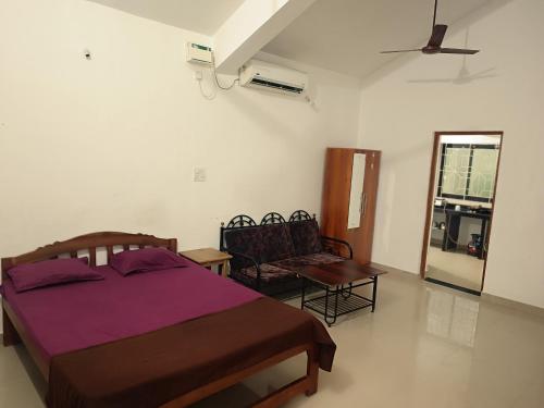 een slaapkamer met een bed, een stoel en een ventilator bij Waves Morjim in Morjim