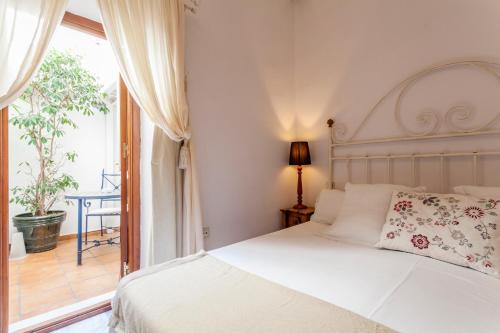 um quarto com uma cama branca e uma varanda em La Casa del Maestro Boutique em Sevilha