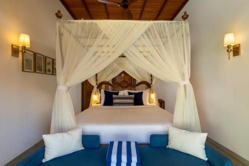 a bedroom with a canopy bed with a blue couch at Oruva Beachside Villa in Galle