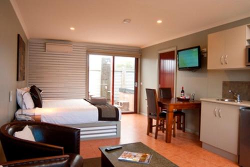 a hotel room with a bed and a table and a kitchen at Bairnsdale Motel in Bairnsdale