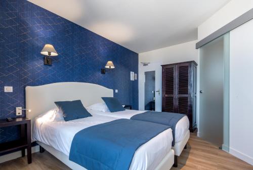a bedroom with two beds and a blue wall at Les Chants d'Ailes - Hôtel Face Mer in La Turballe