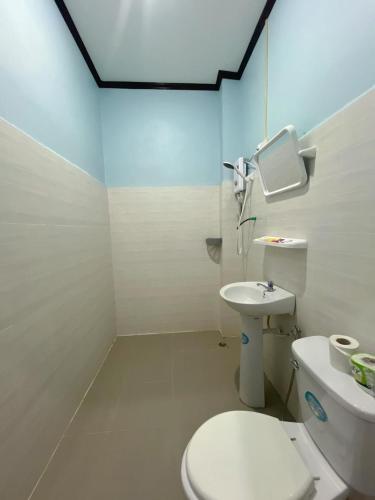 a bathroom with a white toilet and a sink at Smile Guesthouse VangVieng in Vang Vieng