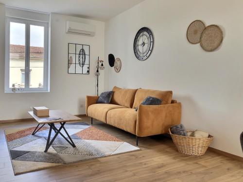 un soggiorno con un divano e un orologio a parete di Appartement Zen & Cosy a Ambérieu-en-Bugey