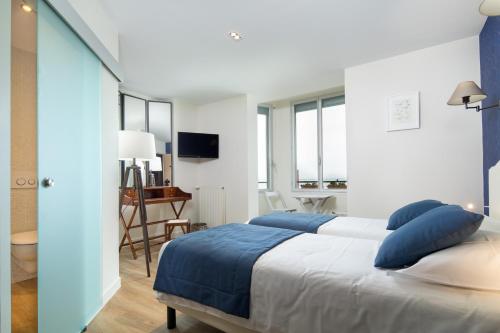 a bedroom with a large bed with blue pillows at Les Chants d'Ailes - Hôtel Face Mer in La Turballe