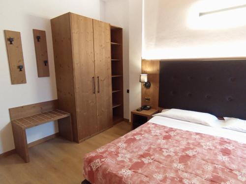 ein Schlafzimmer mit einem Bett und einem Holzschrank in der Unterkunft Hotel Serena in Dimaro