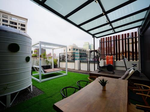 a rooftop patio with a table and green grass at 3 Door Hotel in Tainan