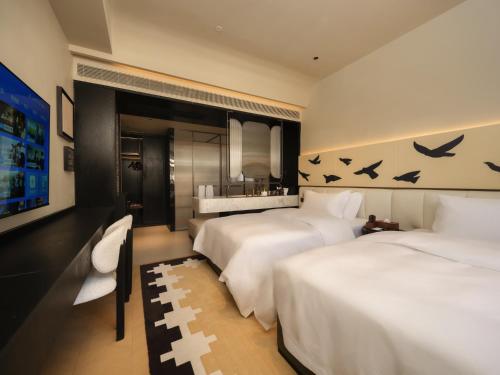 a hotel room with two beds and a tv at 龄舍1927酒店 in Wuhan