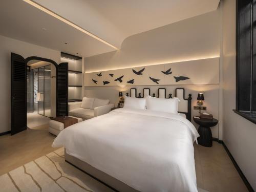 a bedroom with a large white bed with birds on the wall at 龄舍1927酒店 in Wuhan