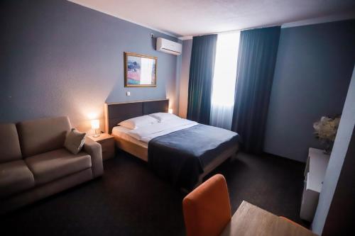 a bedroom with a bed and a couch and a chair at Wellness&Spa Hotel Astorya in Banja Luka