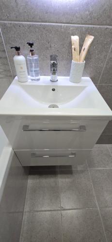 un lavandino bianco in bagno con due bottiglie di Mažeikiai City Apartments a Mažeikiai