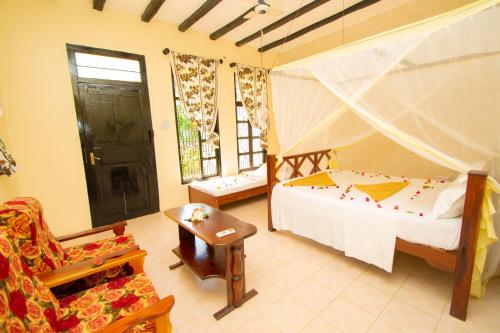 een slaapkamer met een bed, een stoel en een raam bij Severini Villas Zanzibar in Nungwi