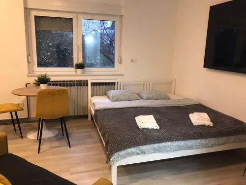 een slaapkamer met 2 bedden, een tafel en een raam bij Warm'n Fuzzy Studio in Central Sesvete in Sesvete