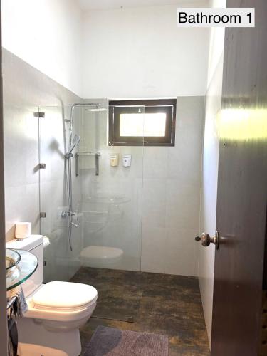 a bathroom with a toilet and a glass shower at Silverlane Beach House in Matara
