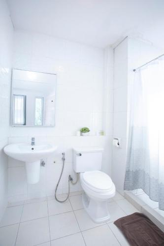 a white bathroom with a toilet and a sink at Rangsit Apartment II in Ban Talat Rangsit