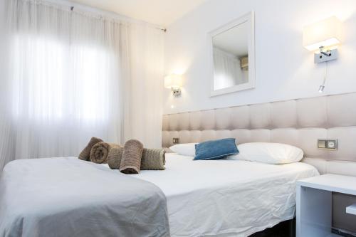 1 dormitorio con 2 camas con sábanas blancas y espejo en Du Soleil Apart, en Sitges