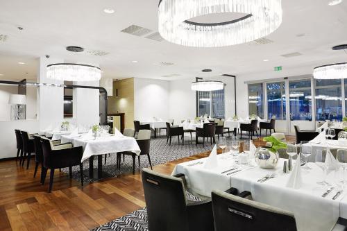 コウォブジェクにあるDiune Resort by Zdrojowaの白いテーブルと椅子、窓のあるレストラン
