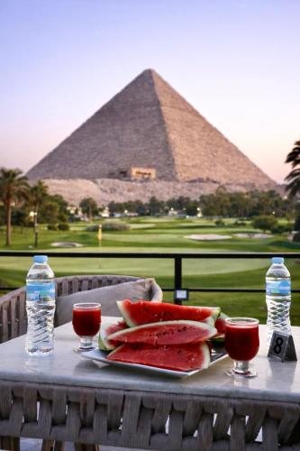 een tafel met een bord watermeloen en een piramide bij Dayy Pyramids View Hotel in Caïro