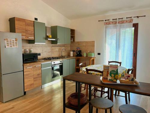 une cuisine avec des armoires vertes et une table avec des chaises dans l'établissement Appartamento il Lentischio a 5 minuti dal mare con Aria Condizionata, à Cardedu