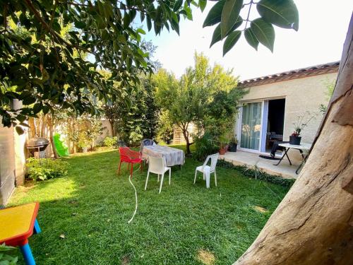 een tuin met een tafel en stoelen in het gras bij loft, air conditioning, garden, optional jacuzzi, barbecue in Lunel